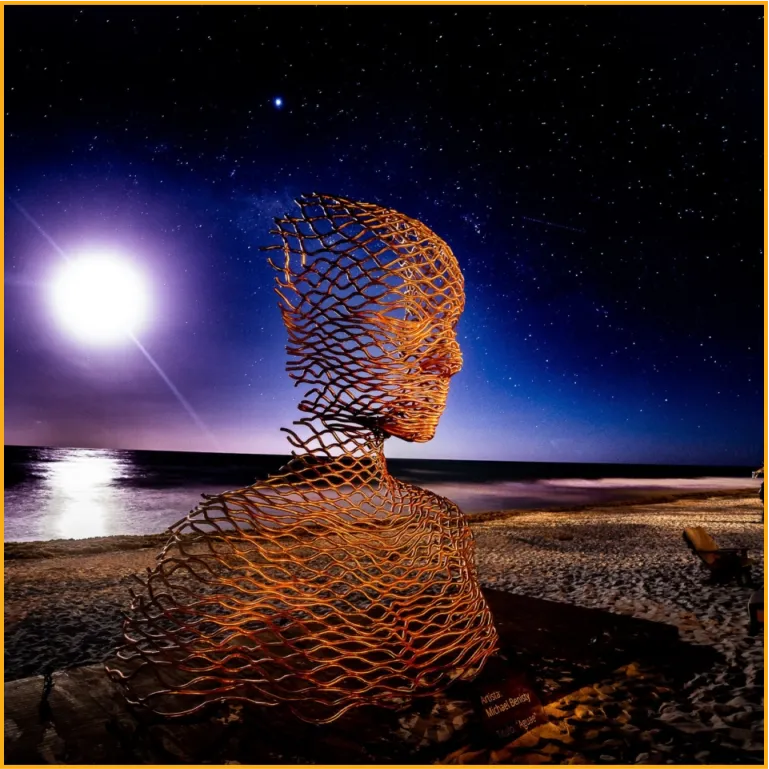 Wire sculpture of a woman on the beach moon and sea in the background