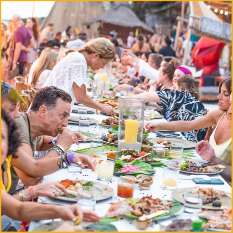 People eating at a long table in the open
