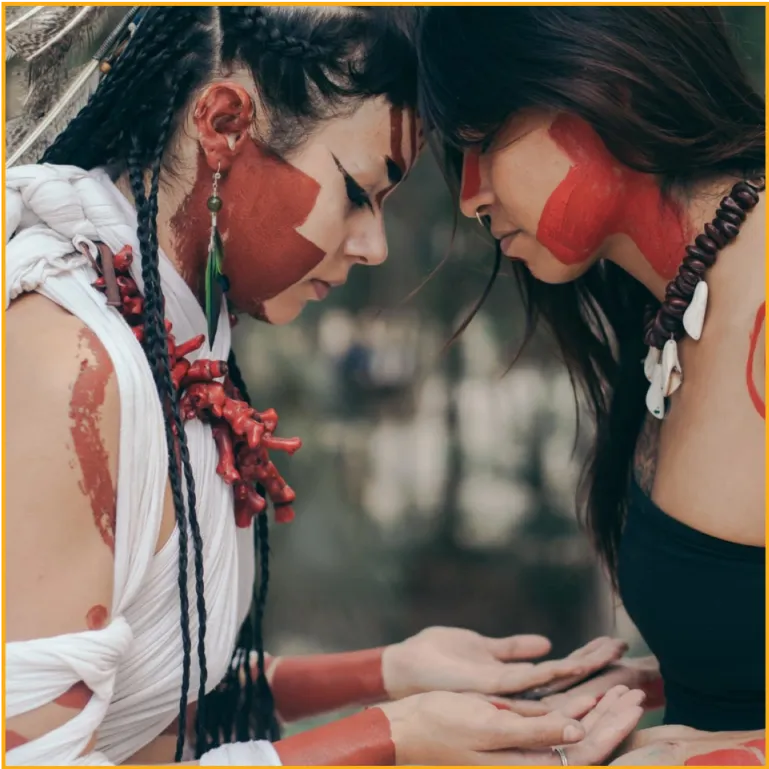 two girls with coral necklaces and red face paint one in white and the other in black