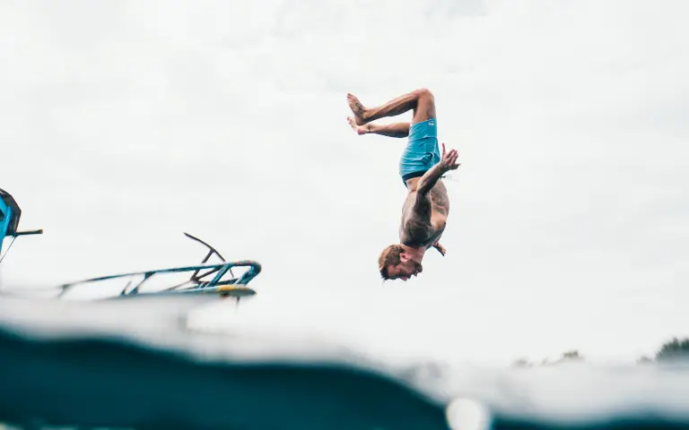 man jumping off the dock and somersaulting in air