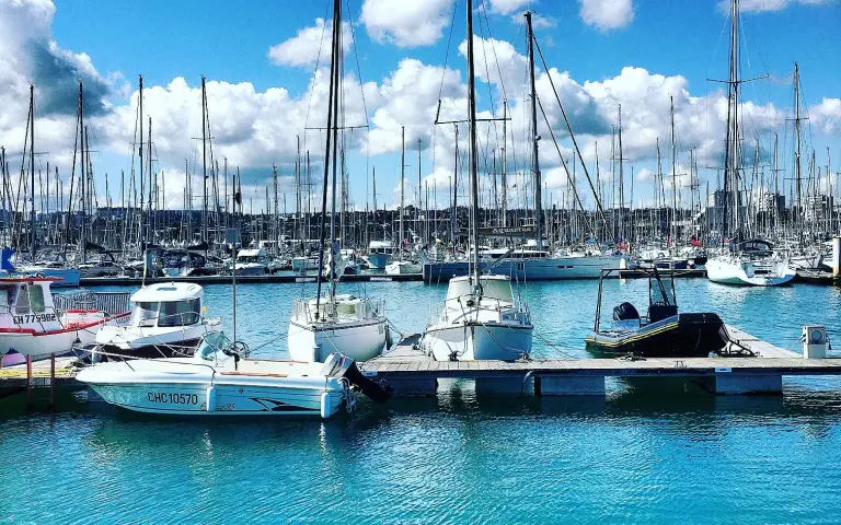 Boats docked in the marina with clouds in the background